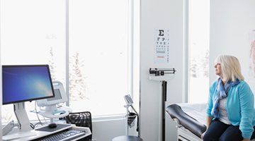 A wide shot of a woman in a hospital room gazing out the window, implying behavioural science's potential to affect patient behaviour
