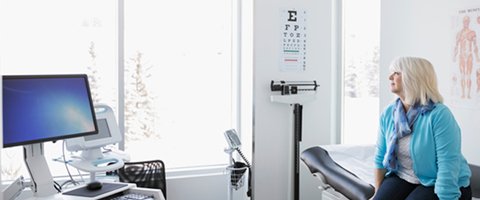 A wide shot of a woman in a hospital room gazing out the window, implying behavioural science's potential to affect patient behaviour