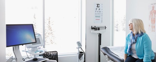 A wide shot of a woman in a hospital room gazing out the window, implying behavioural science's potential to affect patient behaviour
