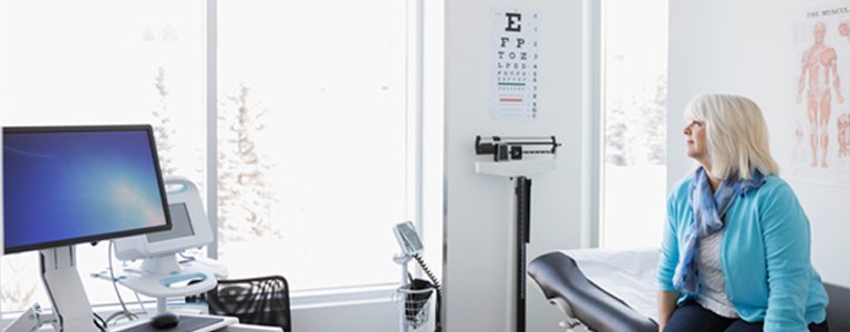 A wide shot of a woman in a hospital room gazing out the window, implying behavioural science's potential to affect patient behaviour